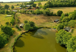 Aerial view of Feather Down La Flocellière en Vendée, showcasing the lake, cabins, and fields in Pays de la Loire.