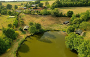 Aerial view of Feather Down La Flocellière en Vendée, showcasing the lake, cabins, and fields in Pays de la Loire.