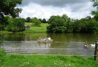 Familia remo en un bote en un lago tranquilo en Feather Down La Flocellière en Vendée, Pays de la Loire, Francia.