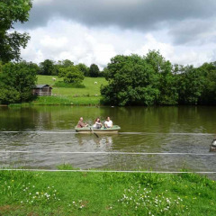 Familia remo en un bote en un lago tranquilo en Feather Down La Flocellière en Vendée, Pays de la Loire, Francia.