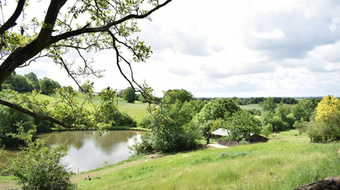 Vista panorámica de colinas verdes, estanque y árboles en Feather Down La Flocellière en Vendée, Pays de la Loire.
