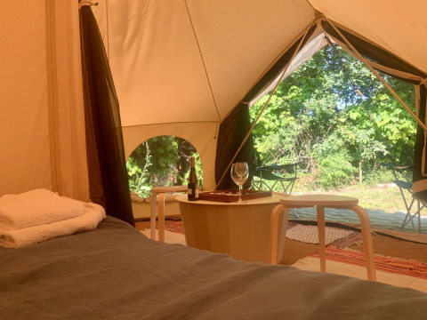 Vista interior de la tienda Camelia XL Bell Tent en Glamping de Cerveira, Portugal, con cama y mesa.