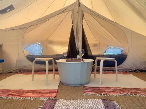Sfeervolle binnenkant van Camelia XL Bell Tent bij Glamping de Cerveira, Portugal, met bedden en zithoek.