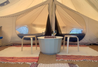 Sfeervolle binnenkant van Camelia XL Bell Tent bij Glamping de Cerveira, Portugal, met bedden en zithoek.