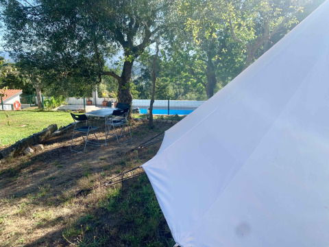 Zona de acampada glamping en Glamping de Cerveira, norte de Portugal, con tienda, sillas y piscina.