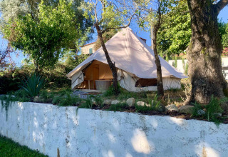 Stort glampingtelt omgivet af træer og grønt i Glamping de Cerveira, en feriepark i det nordlige Portugal.