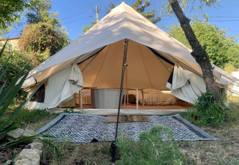 Ampia tenda safari con letti e tappeto all'aperto, al Glamping de Cerveira, immersa nella natura portoghese.