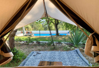 Zicht vanuit een safaritent op een zwembad en tuin bij Glamping de Cerveira in Portugal.