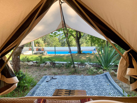 View from the entrance of a safari tent towards a pool and garden at Glamping de Cerveira, Portugal.