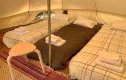 Indretning med tre enkeltsenge og bord i Oliveira Bell teltet på Glamping de Cerveira, Portugal.
