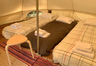 Drie éénpersoonsbedden en een klein tafeltje in Oliveira Bell tent bij Glamping de Cerveira, Portugal.