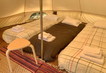 Indretning med tre enkeltsenge og bord i Oliveira Bell teltet på Glamping de Cerveira, Portugal.