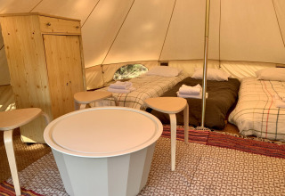 Binnenzicht van de Oliveira Bell Standard Bell Tent met drie bedden en houten meubels bij Glamping de Cerveira.