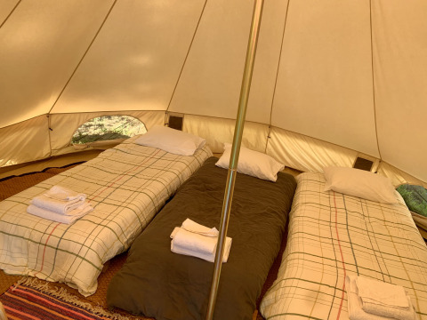 Interior de la tienda Oliveira Bell Standard en Glamping de Cerveira, Portugal, con tres camas individuales.