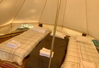 Innenansicht des Oliveira Bell Standard Bell Tents bei Glamping de Cerveira, ausgestattet mit drei Betten.