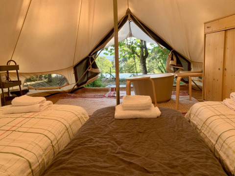 Interior de la tienda Oliveira Bell Standard en Glamping de Cerveira, Portugal, con dos camas y bañera.