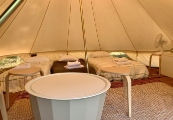 Interior de la tienda Oliveira Bell Standard Bell en Glamping de Cerveira, Portugal, con camas y mobiliario sencillo.