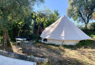 Großes, weißes Glamping-Zelt mit Außenbereich unter schattigen Bäumen bei Glamping de Cerveira, Portugal.