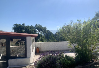 Terrazza soleggiata con piante e vista montagna al Glamping de Cerveira, parco vacanze nel nord del Portogallo.