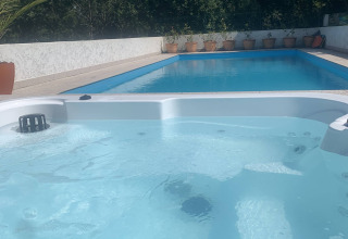 Opvarmet jacuzzi i forgrunden og en udendørs swimmingpool i baggrunden på Glamping de Cerveira, Portugal.