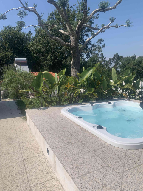 Outdoor jacuzzi at Glamping de Cerveira holiday park in North Portugal, surrounded by greenery and trees.