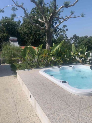 Jacuzzi extérieur au Glamping de Cerveira, parc de vacances au nord du Portugal, entouré de verdure.