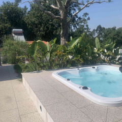 Jacuzzi exterior en Glamping de Cerveira, un parque de vacaciones en el norte de Portugal, rodeado de plantas.