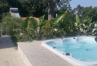 Outdoor jacuzzi at Glamping de Cerveira holiday park in North Portugal, surrounded by greenery and trees.