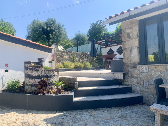 Außenbereich von Glamping de Cerveira in Nordportugal mit Steinterrasse, Stufen und Pergola.
