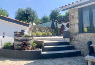 Udendørs område ved Glamping de Cerveira i Nordportugal med stenterrasse, trapper og pergola.
