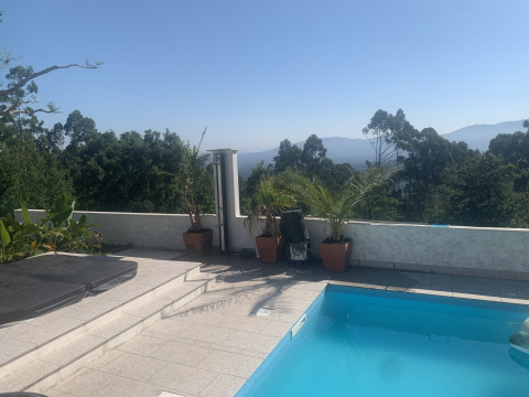 Vue sur une piscine, des plantes et des montagnes au Glamping de Cerveira dans le nord du Portugal.