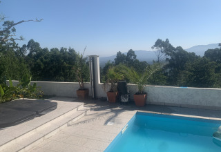 Udsigt over et poolområde med planter, skov og bjerge på Glamping de Cerveira i det nordlige Portugal.