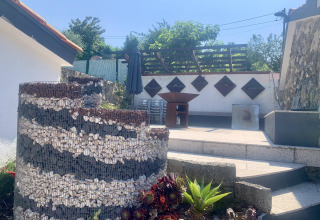 Udendørs område ved Glamping de Cerveira, Portugal, med stensætning, planter og terrasse under solskin.