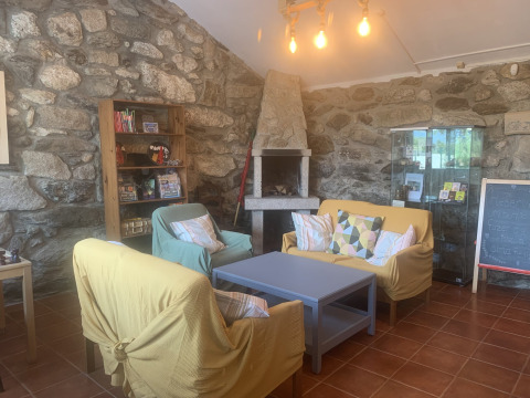 Acogedora sala de estar con paredes de piedra, chimenea, sofás coloridos y estantería en Glamping de Cerveira, Portugal.