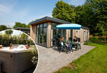 Udendørs terrasse ved en moderne lodge med spabad, hvor folk nyder både afslapning og hyggesnak.