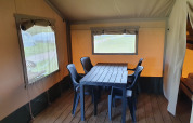 Indretning af safaritelt med spisebord og stole på Camping de Oude Rijn, Holland, trægulv og vinduer.