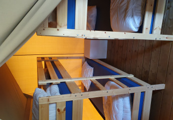 Interior de una tienda safari en Camping de Oude Rijn, Países Bajos, con literas de madera y ropa de cama.