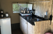 Angolo cucina in una tenda safari al Camping Bockenauer Schweiz con piano in legno, lavello e frigo.