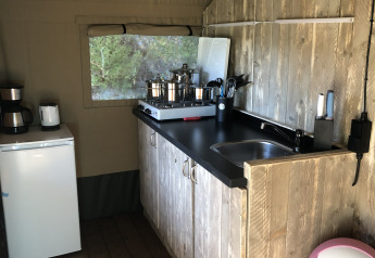 Kitchen area in a safari tent at Camping Bockenauer Schweiz with wooden counter, sink, and fridge.