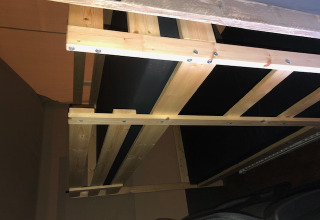 Vista interior de una cama de madera en una tienda safari con instalaciones sanitarias en Camping Bockenauer Schweiz.