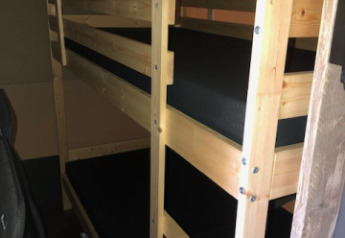 Interior view of a wooden bed frame in a safari tent with sanitary facilities at Camping Bockenauer Schweiz.