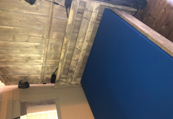 Interior de una tienda safari con paneles de madera, colchón azul y focos en Camping Bockenauer Schweiz, Alemania.