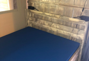 Interno di una tenda safari con pannelli in legno, materasso blu e faretti al Camping Bockenauer Schweiz, Germania.