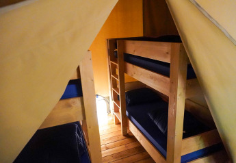 Binnenaanzicht van de Safari-tent op Camping Pittoresque in Frankrijk met stapelbedden en houten vloer.