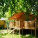 Tenda safari al Camping Pittoresque in Francia, terrazza in legno tra alberi verdi e ombreggiati.