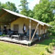 Tienda safari en Camping Emmen, Países Bajos, con terraza y sillas, rodeada de naturaleza verde.