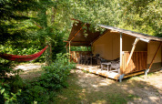 Safari telt ved Camping Fargogne i Frankrig med terrasse, havemøbler og hængekøje i grønne omgivelser.