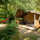 Safari-Zelt auf Camping Fargogne in Frankreich mit Veranda, Gartenmöbeln und Hängematte im Grünen.