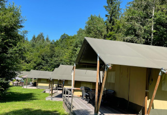 Tiendas safari en Camping Bockenauer Schweiz, Alemania, dispuestas en fila bajo un cielo azul despejado.