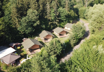 Vista aérea de tiendas safari en Camping Bockenauer Schweiz, Alemania, rodeadas de frondosos bosques.